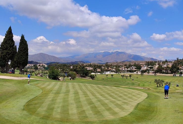 People playing golf on the green Mijas Golf Club course while magnificent natural landscape surrounds them