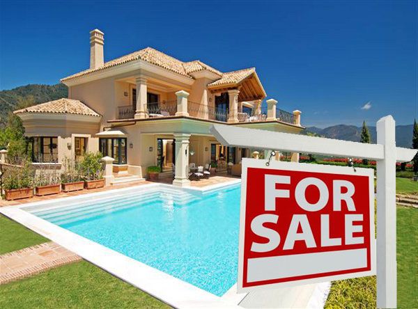 Front side of a luxury villa with a for sale sign in Marbella, Spain